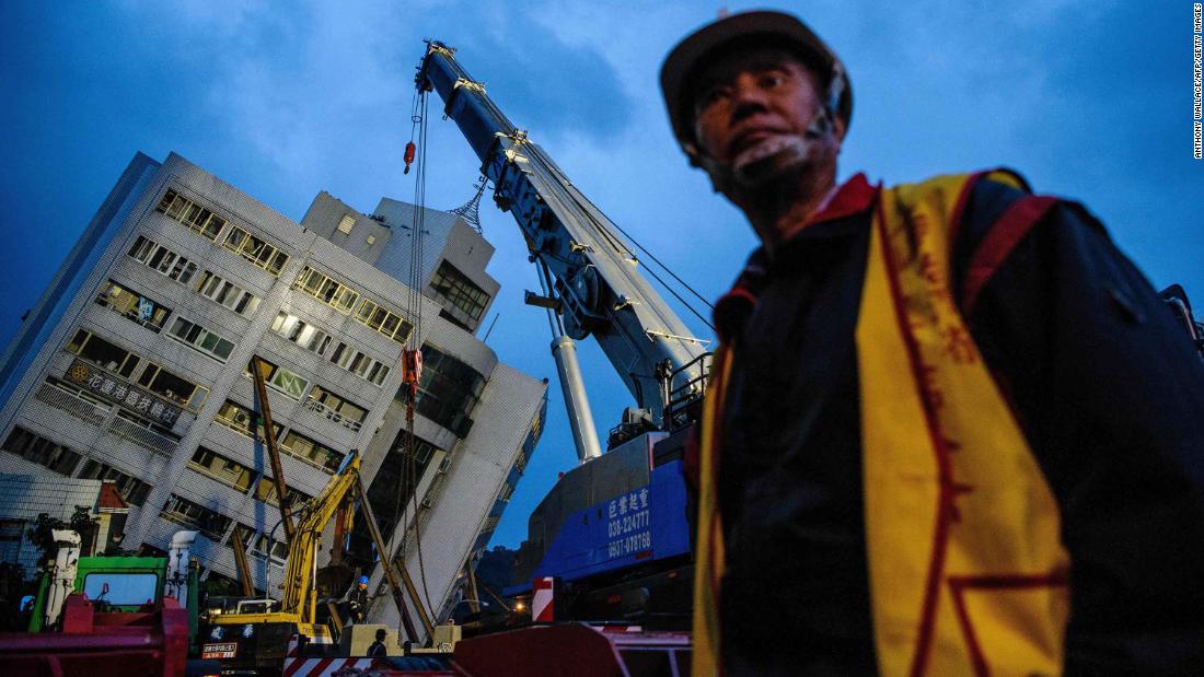 An emergency worker walks near a crane that was working to support the Yun Tsui building in Hualien. The residential building was shifted off its foundation during the quake.