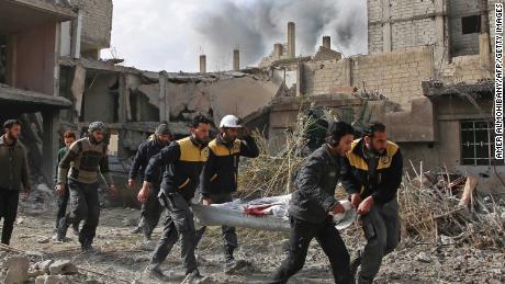 White Helmets members evacuate a victim of an airstrike Thursday in the rebel-held enclave of Hazeh.