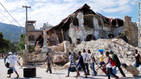 People walk by the collapsed Sacre Coeur Church in Port-au-Prince two days after the earthquake that devastated Haiti on January 12, 2010. 