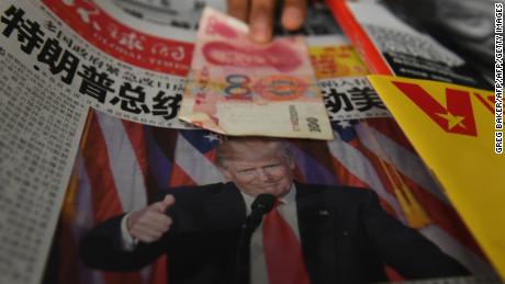 TOPSHOT - A vendor picks up a 100 yuan note above a newspaper featuring a photo of US president-elect Donald Trump, at a news stand in Beijing on November 10, 2016.
The world&#39;s second-largest economy is US president-elect Donald Trump&#39;s designated bogeyman, threatening it on the campaign trail with tariffs for stealing American jobs, but analysts say US protectionism could create opportunities for Beijing. / AFP / GREG BAKER        (Photo credit should read GREG BAKER/AFP/Getty Images)