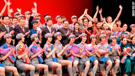 North Korean leader Kim Jong Un, center, claps while posing with his wife Ri Sol Ju, government officials and members of a Chinese art troupe for a group photo at East Pyongyang Grand Theater in Pyongyang, North Korea. 
