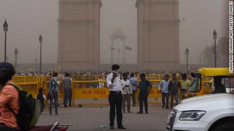 An Indian traffic policeman covering his face as he stands on duty during a dust storm in New Delhi on May 2.