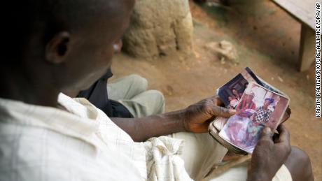 Etienne Ouamouno holds a picture of wife Sia Dembadouno and their son, Emile, in front of their family home in the village of Meliandou, Guinea.