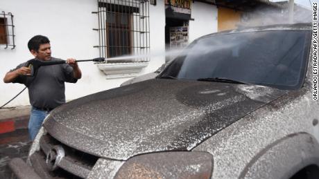 A man cleans ash from the Fuego volcano off of his car in Antigua, Guatemala.