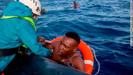A member of Sea-Watch helps a migrant to board a boat after he was recovered in the Mediterranean on November 6, 2017. Five people died during the shipwreck.