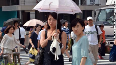 Pedestrians use their parasols to avoid strong sunlight in Tokyo on July 12.