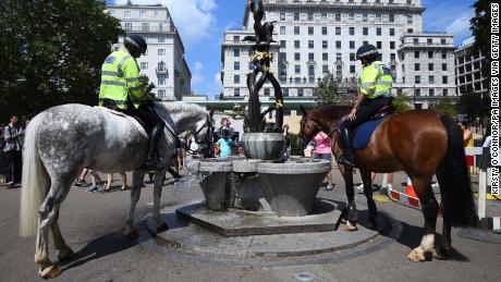Police officers water their horses at a fountain in London&#39;s Green Park.