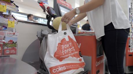 A customer places grocery items into a plastic bag at a self checkout counter in a Coles supermarket in Melbourne.