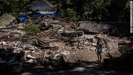 A man stands near the ruins of their houses at a collapsed house following an earthquake on August 8, 2018 in Lombok Island, Indonesia.