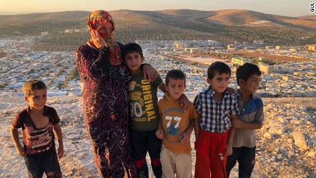 Vaciha Turki-Al Omar, 30, has been in Idlib for seven months. She stands on the hill overlooking the sprawling refugee camp with her kids. &quot;We can try to fight, but the kids are our weakness so we must run away,&quot; she says. 
