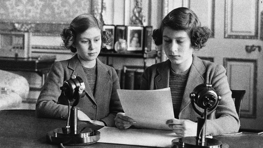 A 14-year-old Elizabeth, 正しい, sits next to her sister for a radio broadcast on October 13, 1940. On the broadcast, her first, she said that England&#39;s children were full of cheerfulness and courage.