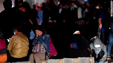 A woman covers her face as she takes refuge on a road following a strong earthquake in Sapporo.