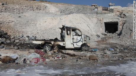 A burned vehicle and personal belongings are seen Saturday in Hass, Syria, after an airstrike.