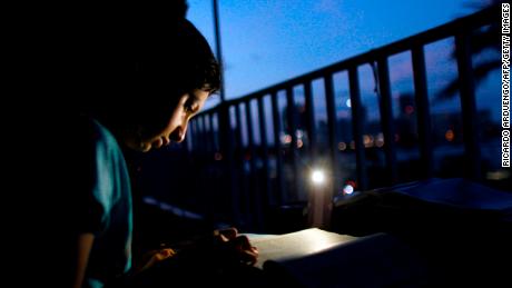 Alana Rivera, 10, does her daily homework on the balcony of her apartment lit by a mobile phone lamp in San Juan last November.