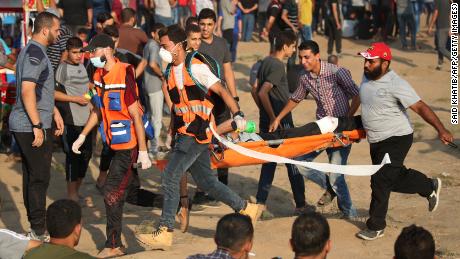 Medics and demonstrators carry an injured Palestinian during clashes Friday on the Israeli border fence.