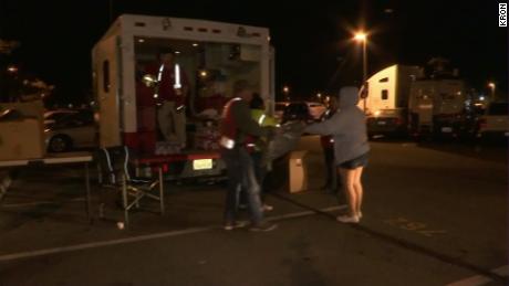 Humanitarian workers bring water and other supplies to a parking lot at a transit station that serves as an evacuation point.