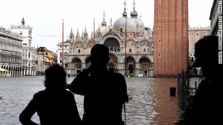 Tourists take pictures in the flooded St Mark&#39;s Square during a high-water alert in Venice on October 29, 2018.