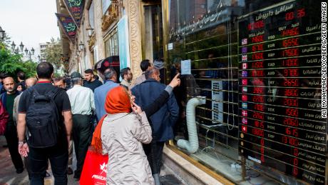 Pedestrians watch exchange rates in a shop window in Tehran on Saturday.