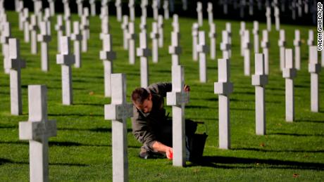 A cemetery employee cleans the cross Friday of an American serviceman killed during World War I, ahead of centenary events at the American Cemetery in Suresnes.