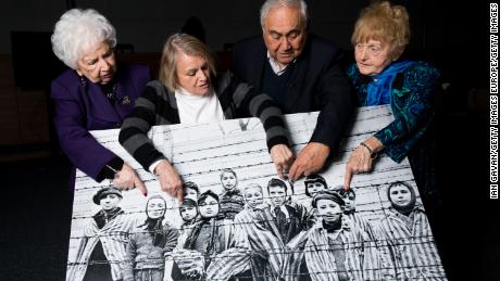 Far right: Eva Kor in 2015 points at an image of herself as a child taken during the liberation of Auschwitz, along with other survivors. 
