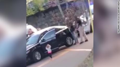   A toddler walks up to the police, his hands in front of the police. air, when his father gets arrested 