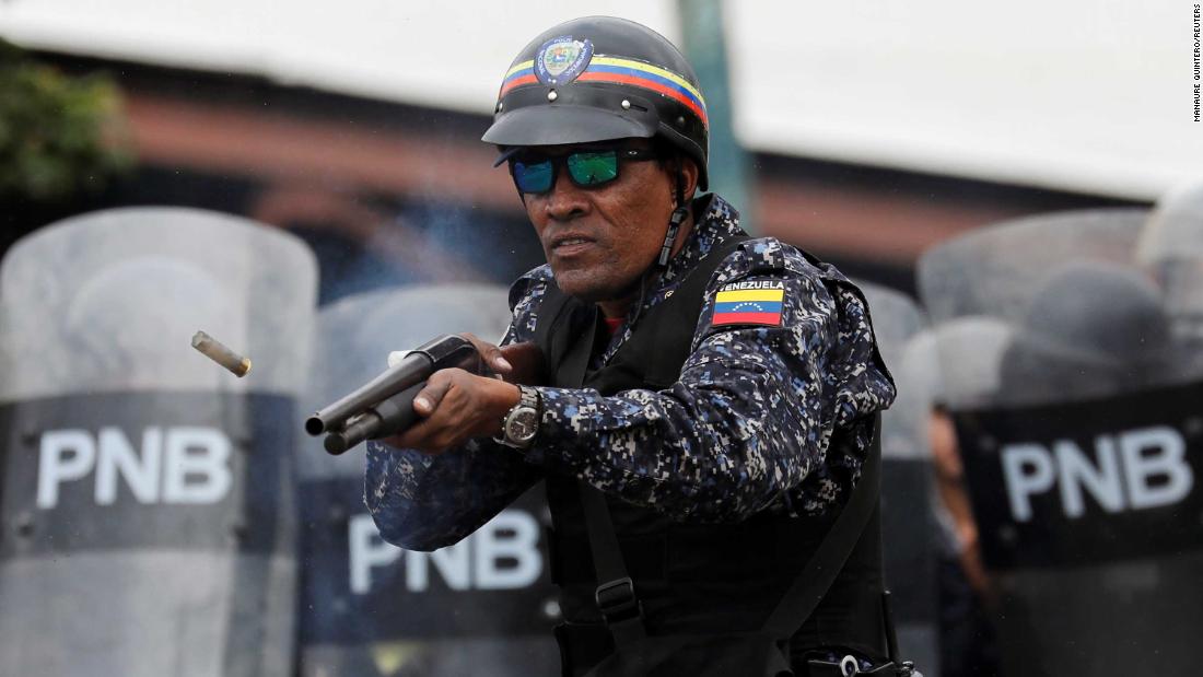A National Police officer fires rubber bullets in Caracas.