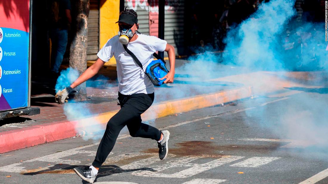 An opposition demonstrator runs with a tear-gas canister on January 23.