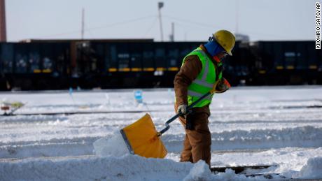   A worker shovels snow on switches. 