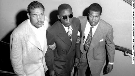 Boxing champion Joe Louis (left) and Neil Scott guide Isaac Woodard up stairs at Hotel Theresa. 