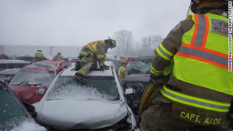 Firefighters climb vehicles during Sunday chain collisions.