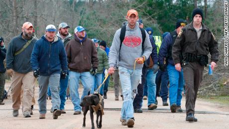 A search and rescue team walks past damage from a tornado in Alabama.