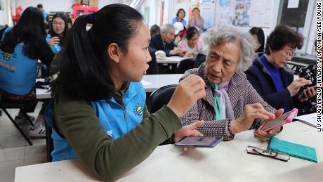 A See Young volunteer explains how to send full-size pictures on WeChat to her retiree student.