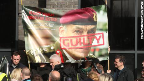 Protesters hold a poster showing British General Sir Michael David Jackson ahead of the announcement on Thursday.
