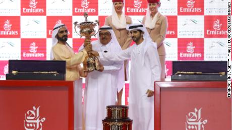 Sheikh Mohammed (L), receives the trophy after his horse Thunder Snow&#39;s victory at the Dubai World Cup.