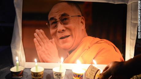 A Tibetan activist lights a candle in front of a poster of spirtual leader The Dalai Lama as members of the Regional Tibetan Youth Congress (RTYC) take part in a candlelight vigil during a protest rally in Hyderabad on March 10, 2016.
