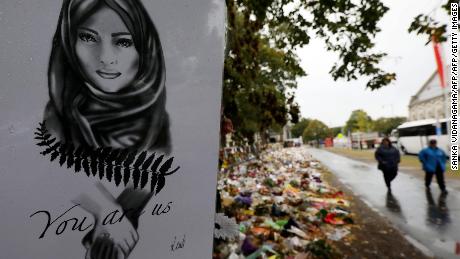 People walk past flowers and tributes displayed in memory of the twin mosque massacre victims outside the Botanical Gardens in Christchurch on April 5, 2019. 