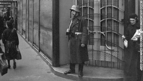 A guard stands outside Schiffmann&#39;s department store, a Jewish business, after it was taken over by the Nazis.