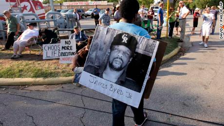 Ricky Jason, a friend of Ross Byrd, carries a photo of James Byrd before Russell Brewer's performance.