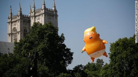Pedestrians walk past as a giant balloon depicting US President Donald Trump as an orange baby floats next to the towers of Westminster Abbey during a demonstration against Trump&#39;s visit to the UK in Parliament Square in London on July 13, 2018. 