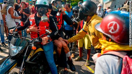 An injured anti-government protester is taken away in a motorcycle after clashing with security forces during the commemoration of May Day in Caracas on May 1, 2019. - Venezuela's opposition leader Juan Guaido called for a massive May Day protest to increase the pressure on President Nicolas Maduro. (Photo by Matias Delacroix / AFP)        (Photo credit should read MATIAS DELACROIX/AFP/Getty Images)
