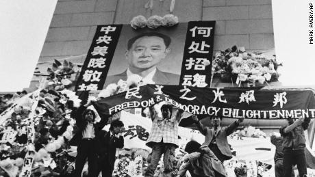 Chinese students hold aloft a banner calling for freedom, democracy and enlightenment on the Martyrs Monument in Beijing&#39;s Tiananmen Square, festooned with a giant portrait of Hu Yaobang, April 19, 1989.