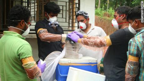 Officials lay a bat in a container after catching it in a well at Changaroth in Kozhikode, in the Indian state of Kerala, on May 21, 2018.