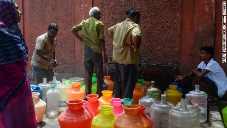 Residents stand around with plastic pots filled with drinking water at a distribution point in Chennai on June 19, 2019.