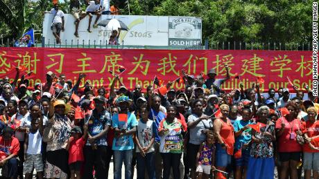 People in Papua New Guinea gather at the roadside to welcome China&#39;s President Xi Jinping in Port Moresby on November 16, 2018, ahead of the Asia-Pacific Economic Cooperation (APEC) Summit. A banner thanks Xi for building their local school. 