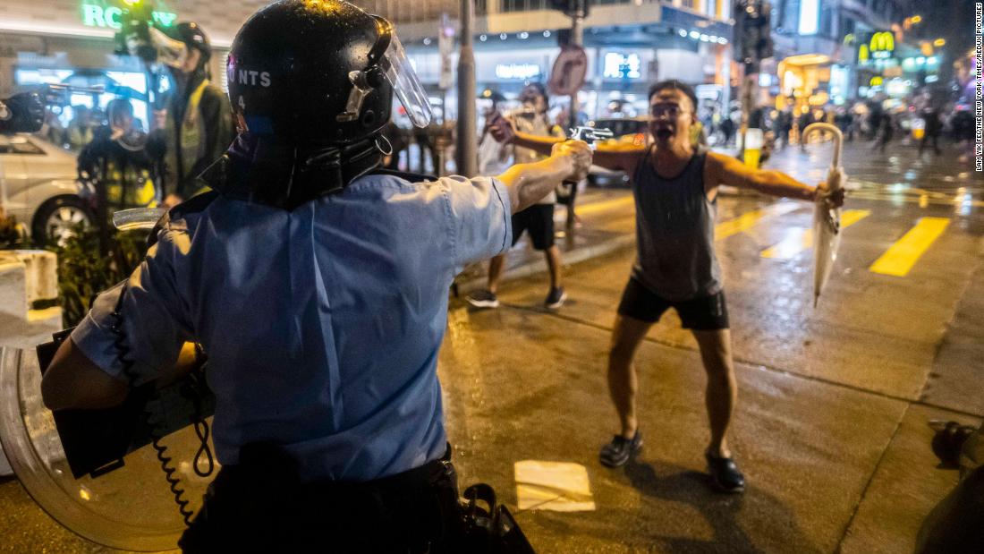 A police officer aims a gun in front of a protester on August 25.