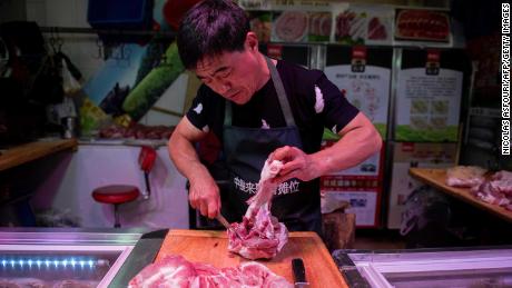 In this picture taken on July 10, 2019, a butcher cuts a piece of pork meat at his stall at a market in Beijing.