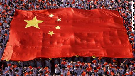 This photo taken on September 1, 2019, shows elementary school students waving national flags as they sing a patriotic song on the first day of the new semester in Handan in China&#39;s northern Hebei province.