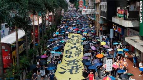 Protesters walk next to a banner with the words &quot;May Glory be to Hong Kong&quot; in Hong Kong on Saturday, October 5. 