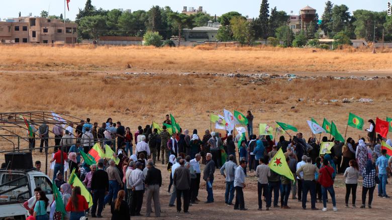 Kurdish people in Ras al-Ayn, Syria, wave their group's flags as they protest against a military operation on Monday, October 7.