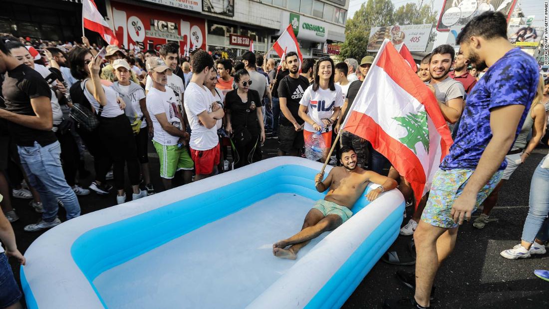 A protester holds a Lebanese flag as he sits in an inflatable pool on a highway in the town of Zouk Mosbeh on October 19.